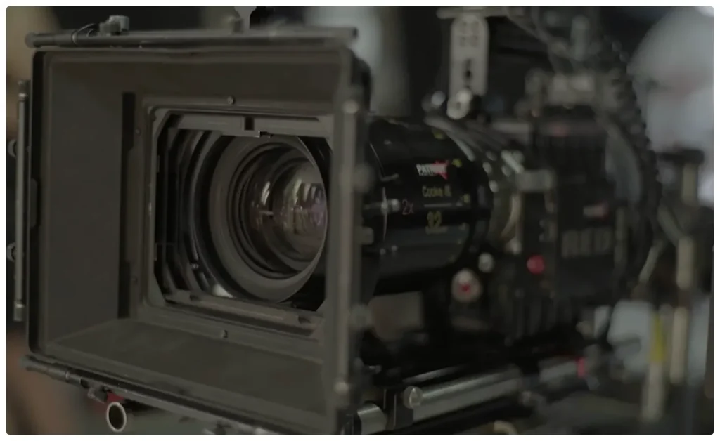 Close-up of a professional cinema camera with a matte box and high-end lens mounted on a film rig, showcasing advanced filmmaking equipment used for commercial and cinematic video production.
